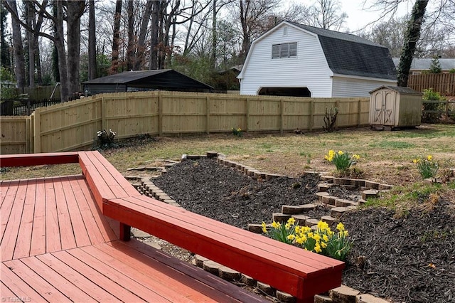 wooden deck with a fenced backyard, an outdoor structure, and a shed