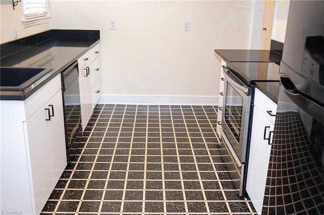 kitchen with dark countertops, black dishwasher, baseboards, and a sink