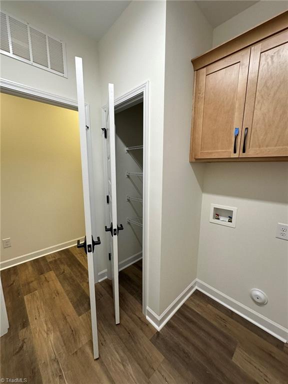 laundry room with dark wood-style flooring, washer hookup, visible vents, baseboards, and cabinet space