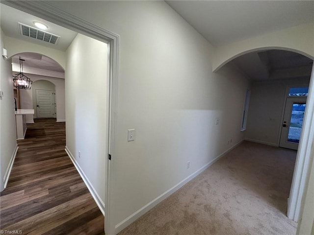 hallway featuring arched walkways, visible vents, and baseboards