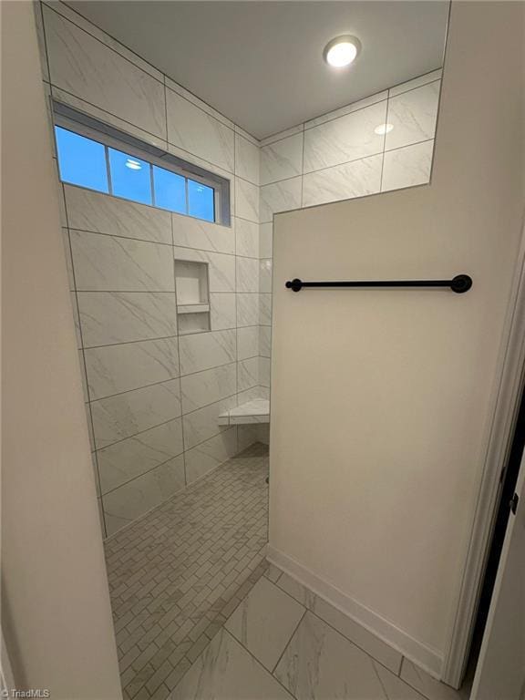 full bathroom featuring marble finish floor, baseboards, and a walk in shower