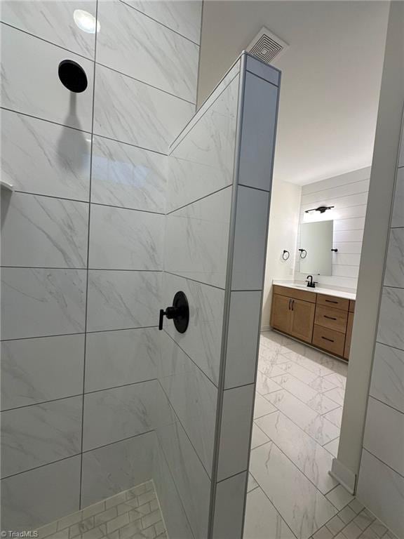 bathroom featuring visible vents, marble finish floor, tiled shower, and vanity