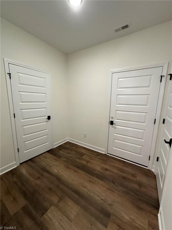 interior space with dark wood-style flooring, visible vents, and baseboards