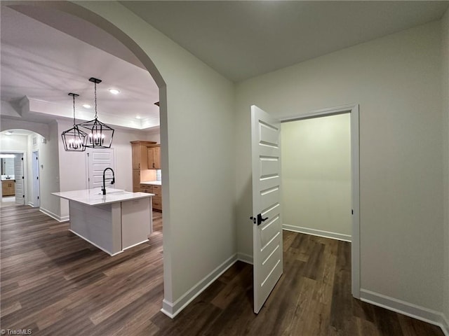 interior space with baseboards, arched walkways, pendant lighting, and a sink