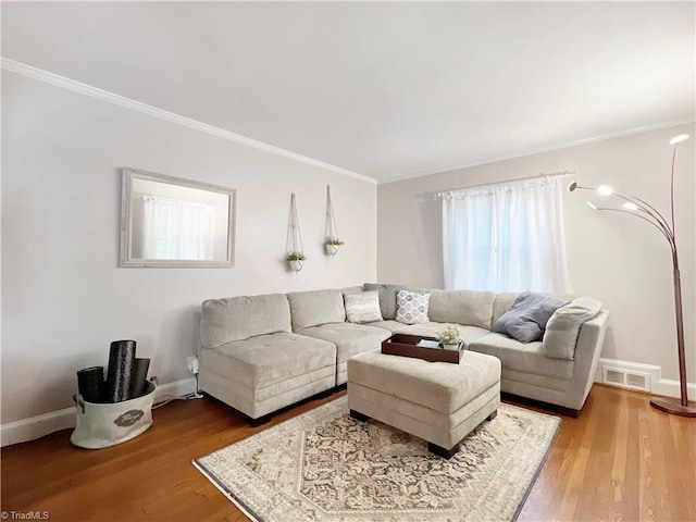 living area featuring crown molding, baseboards, visible vents, and wood finished floors