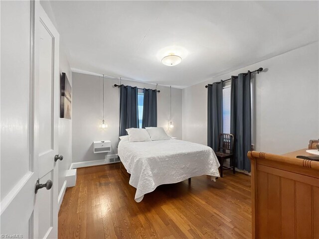 bedroom with visible vents, baseboards, and wood finished floors