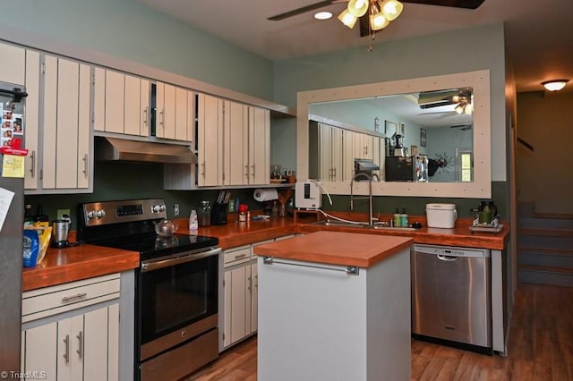 kitchen featuring butcher block counters, a ceiling fan, exhaust hood, and appliances with stainless steel finishes