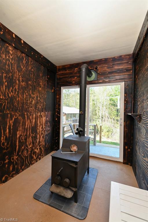 office area featuring wooden walls, carpet flooring, a wealth of natural light, and a wood stove