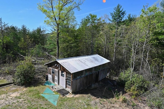 view of outdoor structure featuring a forest view and an outbuilding