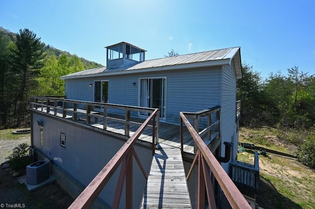 back of property featuring central AC, a wooden deck, and metal roof