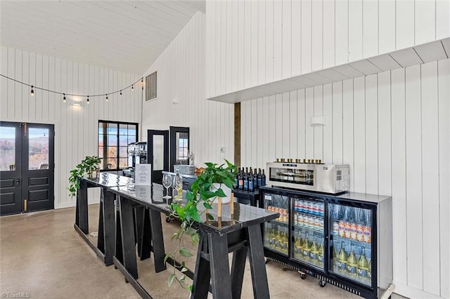 kitchen with wooden walls, a towering ceiling, and concrete floors