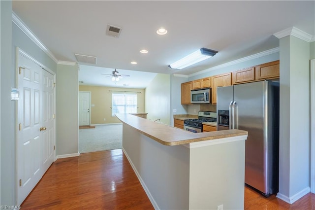 kitchen with visible vents, baseboards, appliances with stainless steel finishes, ornamental molding, and light wood-style floors