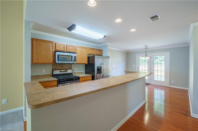 kitchen featuring visible vents, ornamental molding, stainless steel appliances, light countertops, and light wood-style floors