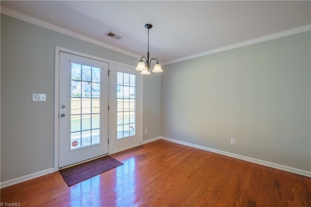 doorway to outside featuring ornamental molding, wood finished floors, visible vents, and baseboards