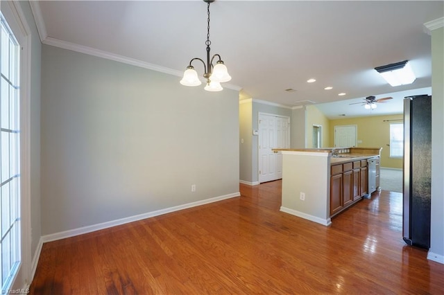 kitchen featuring crown molding, stainless steel dishwasher, freestanding refrigerator, a sink, and wood finished floors