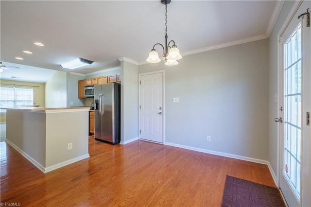 kitchen featuring baseboards, appliances with stainless steel finishes, decorative light fixtures, crown molding, and light wood-type flooring