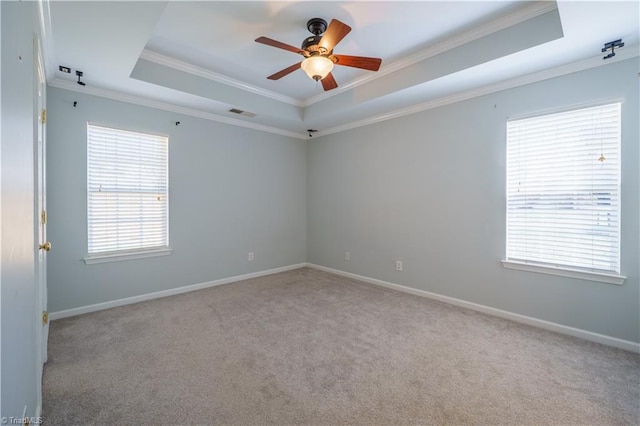 empty room with baseboards, a tray ceiling, carpet, and crown molding