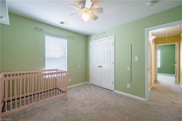 unfurnished bedroom featuring a closet, visible vents, attic access, carpet flooring, and baseboards