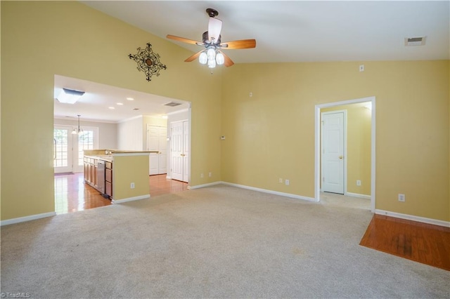 unfurnished living room featuring light colored carpet, vaulted ceiling, baseboards, and ceiling fan