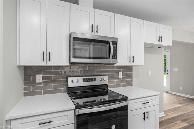 kitchen featuring appliances with stainless steel finishes, light wood-type flooring, white cabinetry, and backsplash