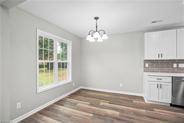 unfurnished dining area with wood-type flooring and an inviting chandelier