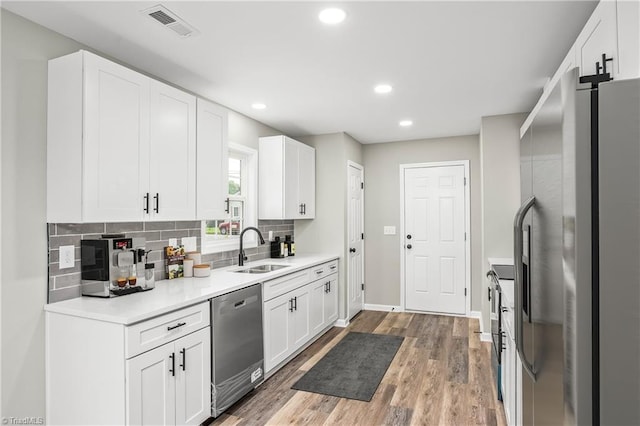 kitchen featuring tasteful backsplash, stainless steel appliances, sink, hardwood / wood-style flooring, and white cabinets