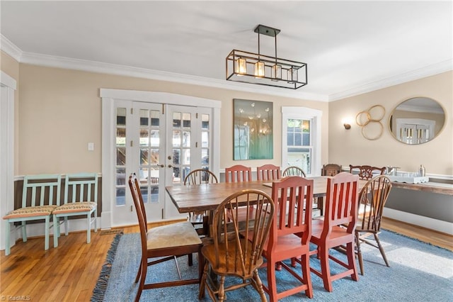 dining space with french doors, crown molding, and wood finished floors