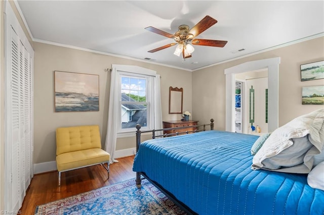 bedroom with ceiling fan, ornamental molding, visible vents, wood finished floors, and baseboards