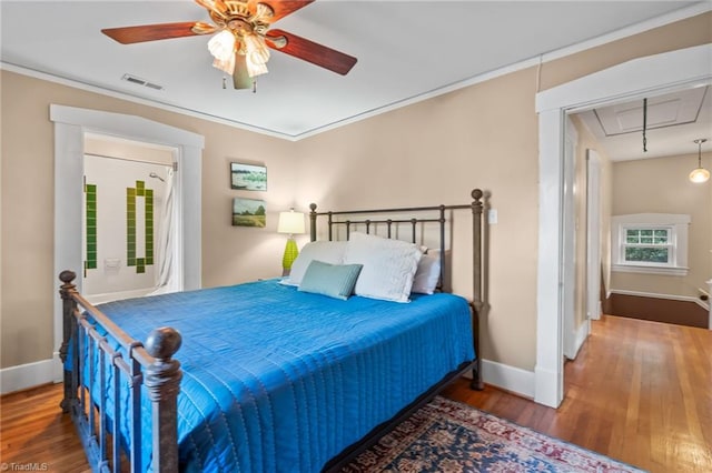 bedroom featuring visible vents, baseboards, attic access, and wood finished floors