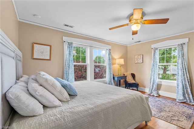 bedroom with visible vents, baseboards, ornamental molding, a ceiling fan, and wood finished floors