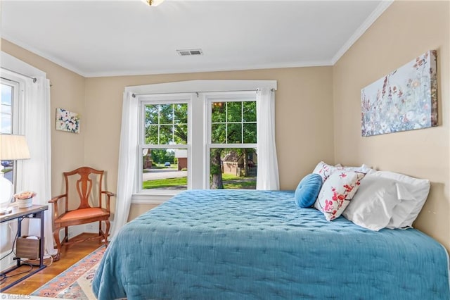 bedroom featuring visible vents, multiple windows, ornamental molding, and wood finished floors