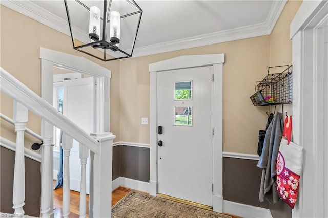 foyer entrance with crown molding, a notable chandelier, wood finished floors, and stairs