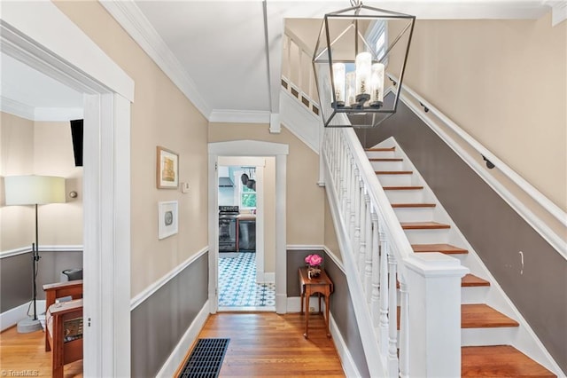 stairs with visible vents, baseboards, a notable chandelier, ornamental molding, and wood finished floors
