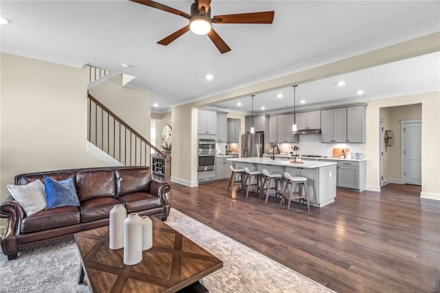 7733 Michaelis St, Greensboro, NC 27455 - living room featuring dark wood-style flooring, ceiling fan, stairs, recessed lighting, and crown molding