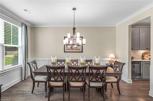 7733 Michaelis St, Greensboro, NC 27455 - dining room featuring wine cooler, dark wood-style floors, a chandelier, crown molding, and a wainscoted wall
