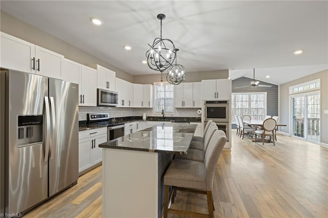 kitchen featuring appliances with stainless steel finishes, a kitchen island, white cabinetry, and light wood-style floors