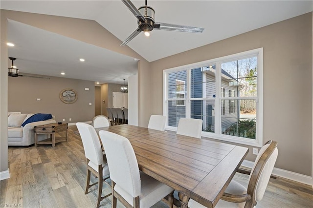 dining space with a ceiling fan, lofted ceiling, light wood-type flooring, and baseboards