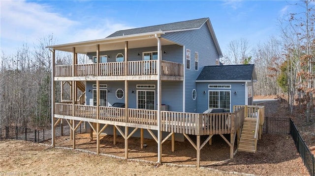 back of house featuring roof with shingles, fence, a deck, and stairs