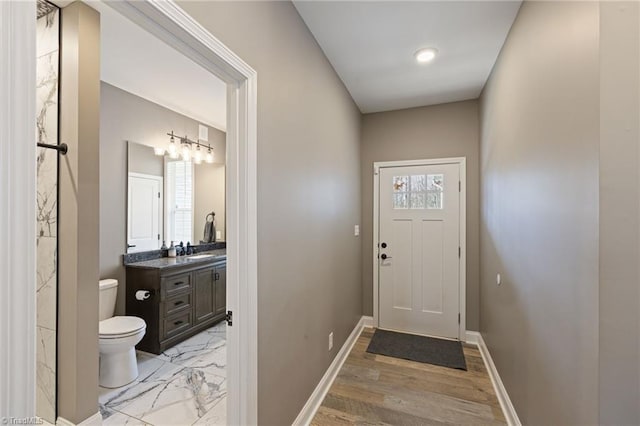 doorway to outside featuring marble finish floor, a sink, and baseboards