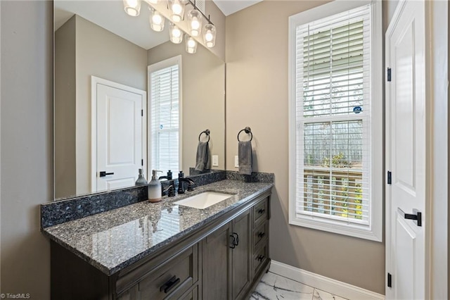 bathroom with marble finish floor, vanity, and baseboards