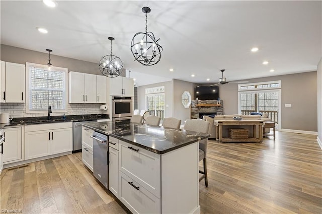 kitchen featuring a fireplace, light wood-style flooring, a kitchen island, a sink, and a kitchen bar