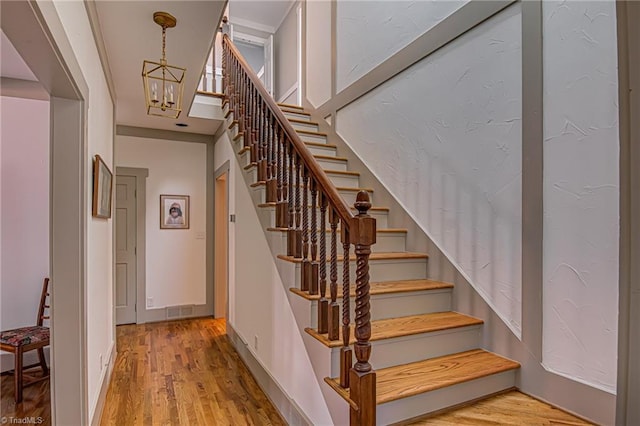 staircase featuring hardwood / wood-style floors and an inviting chandelier