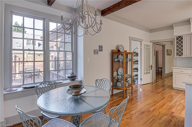 dining space with light hardwood / wood-style floors, a chandelier, and beam ceiling