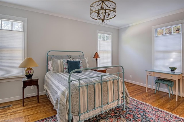 bedroom with light wood-type flooring, ornamental molding, and a notable chandelier