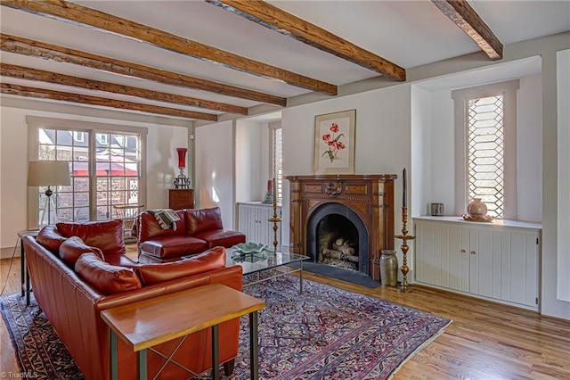 living room featuring beamed ceiling and light hardwood / wood-style flooring