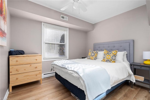 bedroom with baseboard heating, ceiling fan, and wood-type flooring