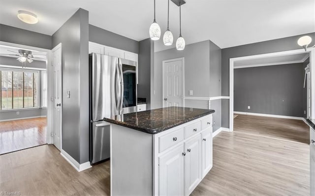 kitchen with white cabinetry, a center island, dark stone countertops, and stainless steel refrigerator