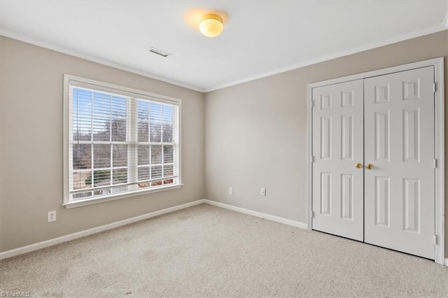 unfurnished bedroom with light colored carpet, ornamental molding, and a closet