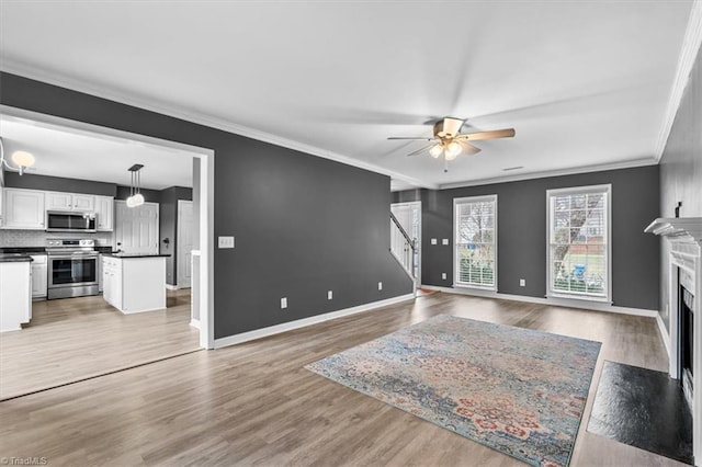 living room featuring a high end fireplace, ceiling fan, wood-type flooring, and ornamental molding