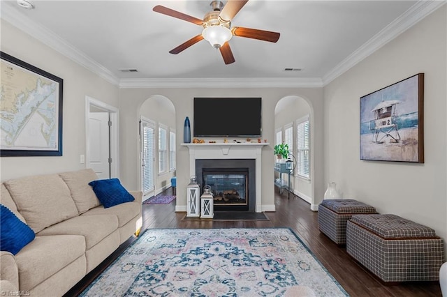 living room with ceiling fan, crown molding, and dark wood-type flooring